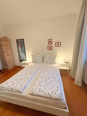 a large white bed in a room with wooden floors at Bolzano with a view in Bolzano