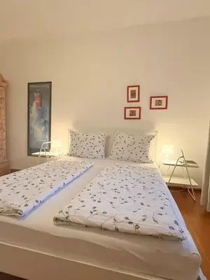 a large white bed in a room with two tables at Bolzano with a view in Bolzano