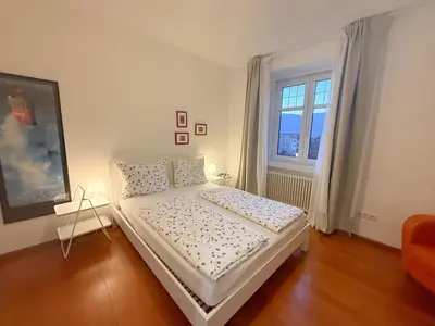 a white bedroom with a bed and a window at Bolzano with a view in Bolzano