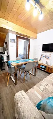 a dining room with a table and chairs and a tv at Trilocale mansardato nel cuore della Val Di Fiemme in Ziano di Fiemme