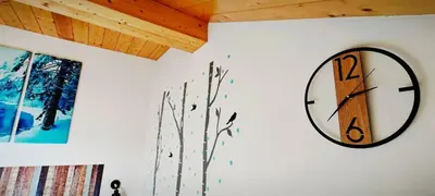 a clock on a white wall next to a window at Trilocale mansardato nel cuore della Val Di Fiemme in Ziano di Fiemme