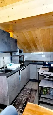 a kitchen with a sink and a wooden ceiling at Trilocale mansardato nel cuore della Val Di Fiemme in Ziano di Fiemme