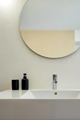a bathroom sink with a round mirror above it at Casa Lies - Apartments in Nova Ponente