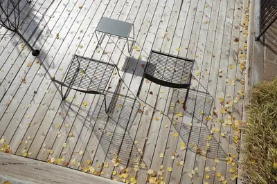 three chairs on a deck with leaves on the ground at Casa Lies - Apartments in Nova Ponente