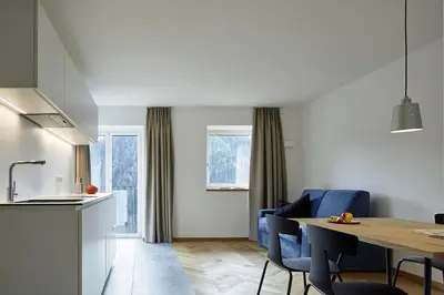 a kitchen and dining room with a table and blue chairs at Casa Lies - Apartments in Nova Ponente
