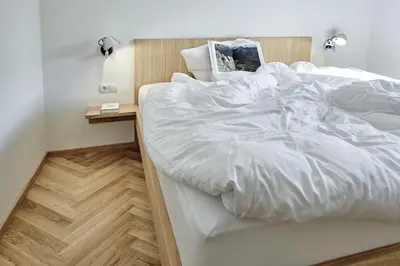 a large bed with white sheets and a night stand at Casa Lies - Apartments in Nova Ponente