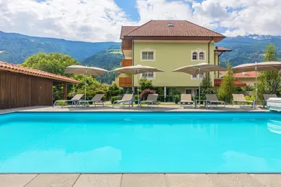 a pool at a hotel with chairs and umbrellas at Wohlfühlhotel Mei Auszeit in Plaus