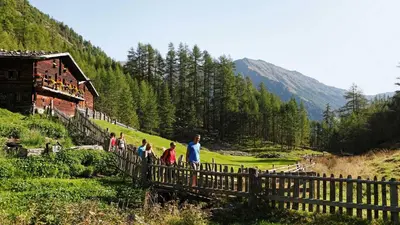 a group of people walking over a wooden fence at Wohlfühlhotel Mei Auszeit in Plaus