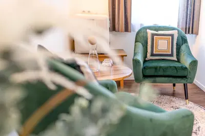 a living room with a green chair and a table at Wohlfühlhotel Mei Auszeit in Plaus