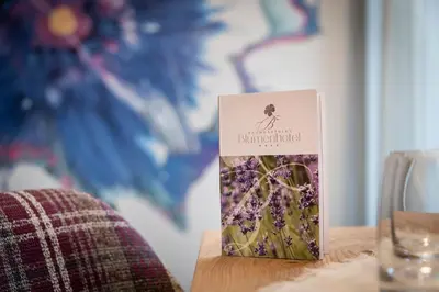 a book sitting on a table next to a glass at Baumgartner's Blumenhotel in Schenna