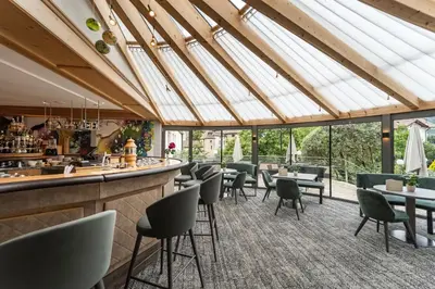 a restaurant with a bar and tables and chairs at Baumgartner's Blumenhotel in Schenna