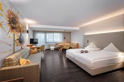a bedroom with a large bed and a living room at Baumgartner's Blumenhotel in Schenna