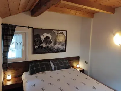 a bedroom with a bed and a painting on the wall at Cèsa Viosadea in Campitello di Fassa