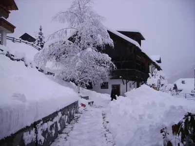 a snow covered yard with a house and a tree at Haus Tasser in San Lorenzo di Sebato