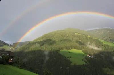 a rainbow in the sky over a green mountain at Haus Tasser in San Lorenzo di Sebato