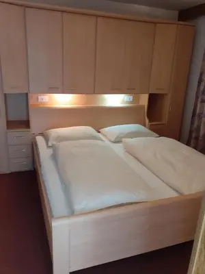 a bed with white sheets and pillows in a room at Haus Tasser in San Lorenzo di Sebato