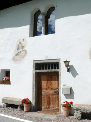 a white building with a wooden door and flowers at Krüglwirt in San Lorenzo di Sebato