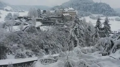 a snow covered mountain with a house and trees at Krüglwirt in San Lorenzo di Sebato