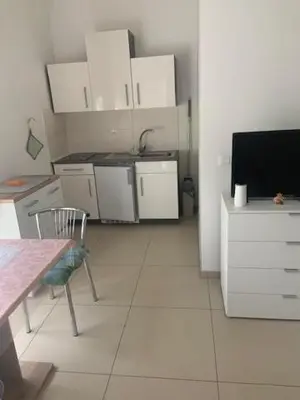 a kitchen with white cabinets and a table and a television at Obsthof Klotz in Frangarto