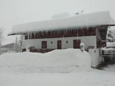 a house with a pile of snow in front of it at Luxury Panoramic 3BR Apt 2min to Centre 5min to Lifts in Cortina dʼAmpezzo