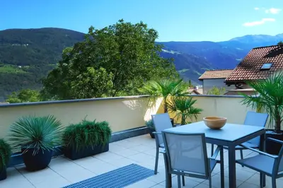 a balcony with a table and chairs and mountains at Apartment Cascada - Alpstay in Parcines