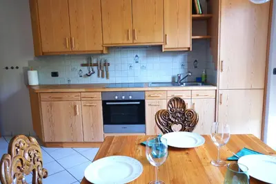 a kitchen with a wooden table with plates and wine glasses at Apartment Cascada - Alpstay in Parcines