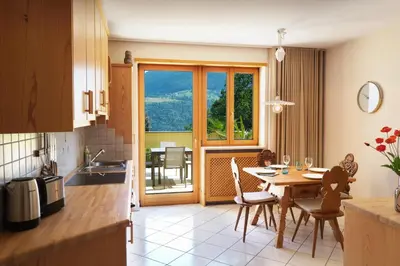 a kitchen with a table and a dining room with a view at Apartment Cascada - Alpstay in Parcines