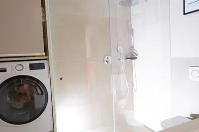 a shower stall with a washing machine in a bathroom at Apartment Cascada - Alpstay in Parcines