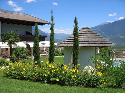 a garden with a gazebo and yellow flowers at Hotel & Appartement Valtnaungut in Cermes