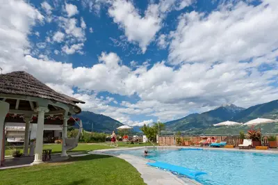 a pool at a resort with mountains in the background at Hotel & Appartement Valtnaungut in Cermes