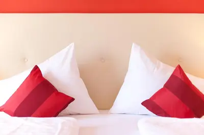 a bed with red and white pillows on it at Hotel & Appartement Valtnaungut in Cermes