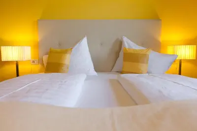 a large bed with white sheets and yellow pillows at Hotel & Appartement Valtnaungut in Cermes