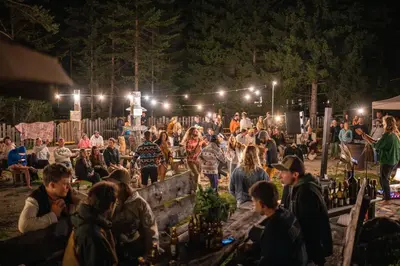 a crowd of people sitting around a fence at night at Camping Sass Dlacia in San Cassiano