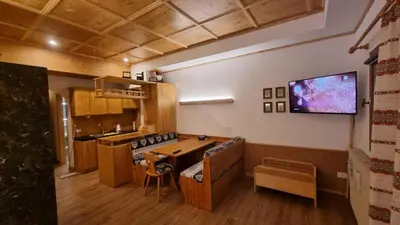a kitchen with a table and a tv on the wall at Casa Cortina - presso Sussy Residence in Falcade