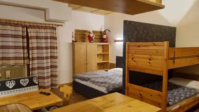 a bedroom with a bunk bed and a table at Casa Cortina - presso Sussy Residence in Falcade