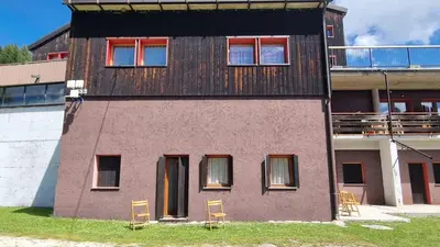 a building with two chairs in front of it at La Casa Degli Orsi - presso Sussy Residence in Falcade