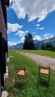 two benches sitting on the grass next to a building at La Casa Degli Orsi - presso Sussy Residence in Falcade