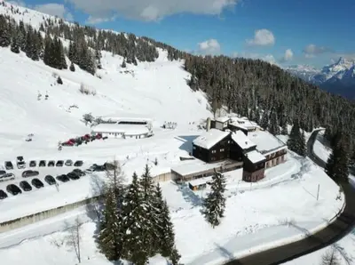 a building on a snow covered mountain with trees at La Casa Degli Orsi - presso Sussy Residence in Falcade