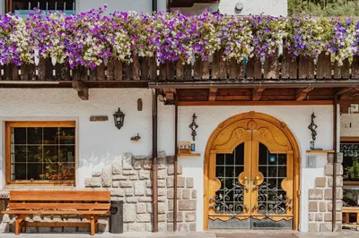a building with a wooden door and a balcony with flowers at Locanda Montana in San Vito di Cadore