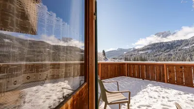 a balcony with a chair and a window with snow at Locanda Montana in San Vito di Cadore