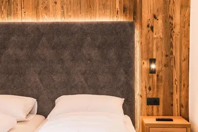 a bedroom with a bed with a wooden wall at Chalet Scherlin in Ortisei