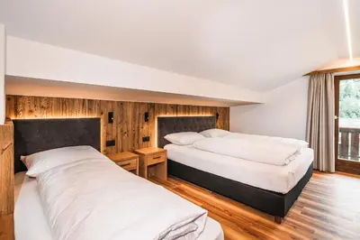 two beds in a room with wooden walls at Chalet Scherlin in Ortisei