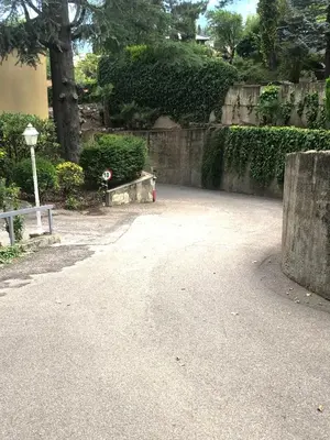 a park with a stone wall and a street at chez Chany in Merano