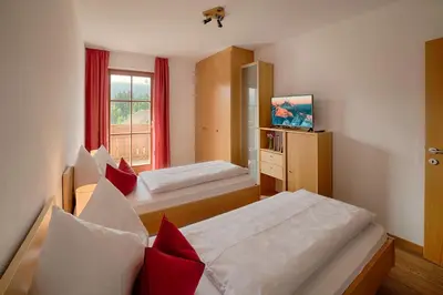a bedroom with a bed with red curtains at Moarberg in Brunico