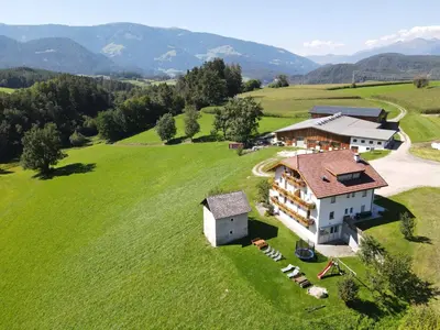 an aerial view of a house on a green field at Moarberg in Brunico