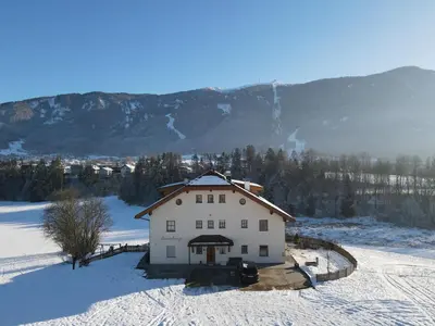 a white house in the snow with mountains in the background at Moarberg in Brunico