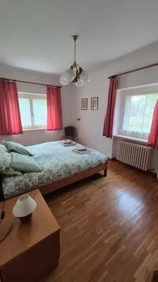 a bedroom with a large bed and red curtains at Appartment Deville with Garden in Moena