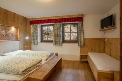 a bedroom with two beds and a flat screen tv at Leithäusl in San Lorenzo di Sebato