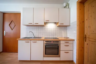 a kitchen with white cabinets and a sink at Apartments Berdan in Santa Cristina in Val Gardena
