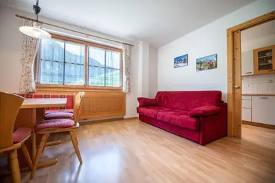 a living room with a red couch and a table at Apartments Berdan in Santa Cristina in Val Gardena